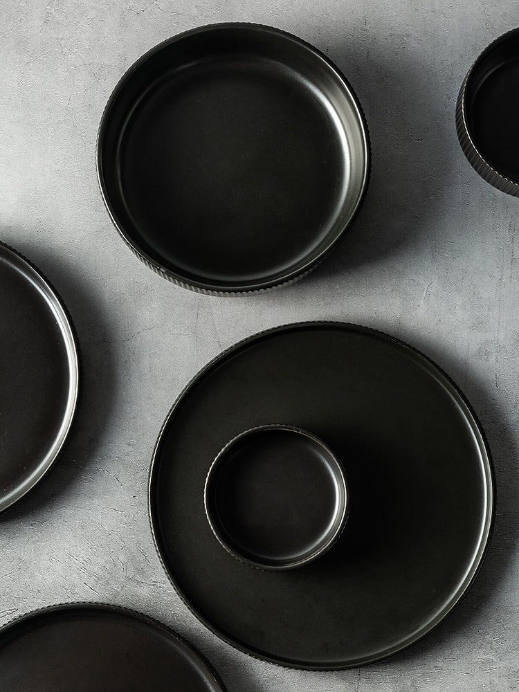 Hualian Yijia Plate Dish Set featuring black plates and bowls arranged artistically on a gray background.